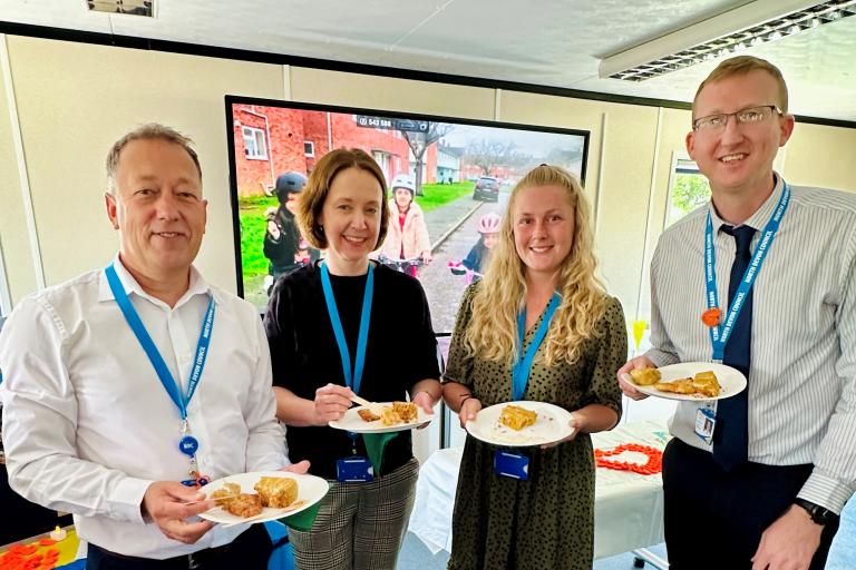 Four council employees holding paper plates with food on